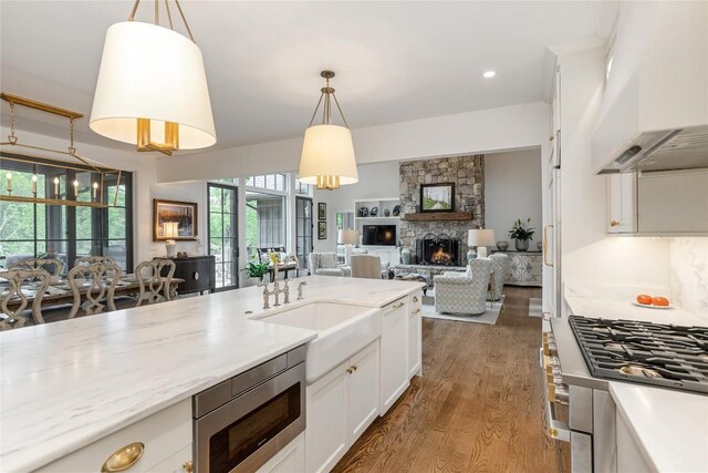 510 Boiling Springs Rd, Sapphire, NC 28774 - kitchen with stainless steel microwave, custom range hood, a stone fireplace, wood finished floors, and hanging light fixtures