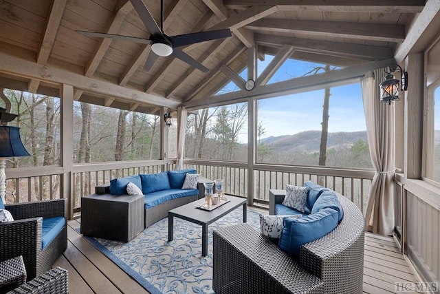 sunroom with ceiling fan, a mountain view, lofted ceiling with beams, and wood ceiling