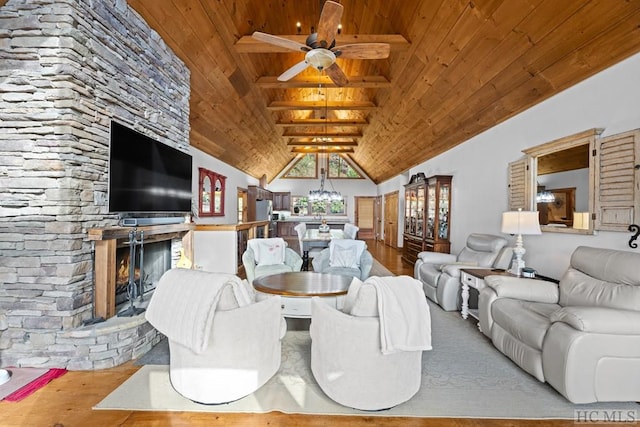 living room featuring light hardwood / wood-style flooring, a stone fireplace, wood ceiling, and vaulted ceiling with beams