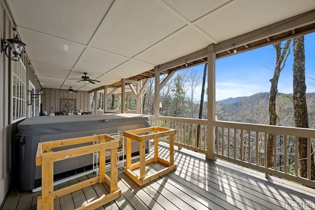 wooden terrace with a hot tub, a mountain view, and ceiling fan