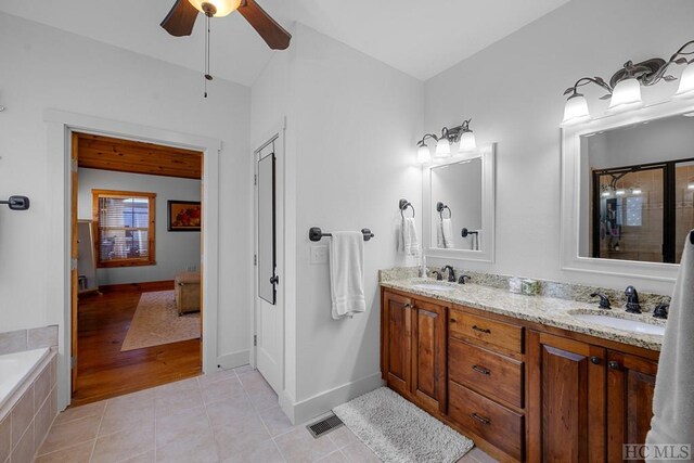 bathroom featuring ceiling fan, vanity, tile patterned flooring, and a relaxing tiled tub