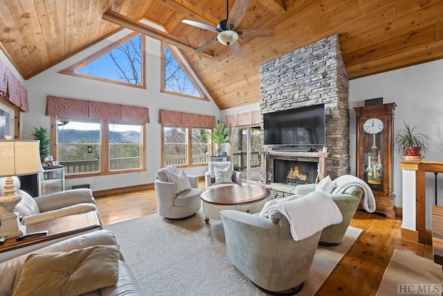 living room with light hardwood / wood-style floors, high vaulted ceiling, wooden ceiling, and a stone fireplace