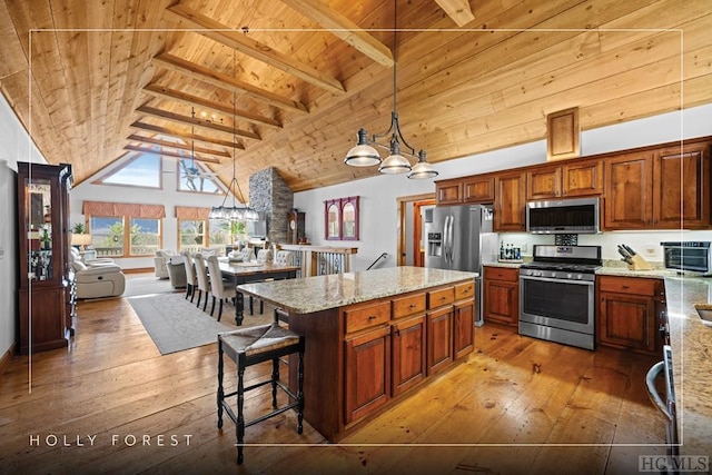 kitchen with hanging light fixtures, stainless steel appliances, a center island, light stone counters, and wooden ceiling