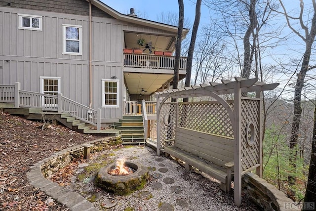 back of property with ceiling fan and a fire pit