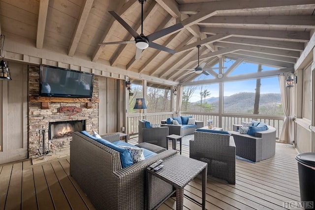 wooden terrace with ceiling fan and an outdoor living space with a fireplace