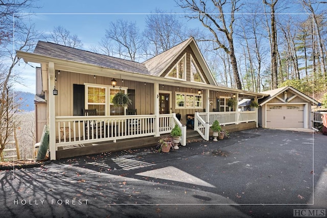 ranch-style home featuring a garage, an outdoor structure, and a porch