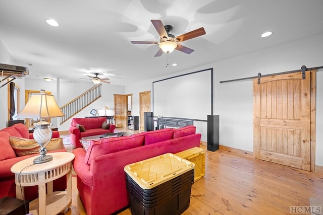 home theater room with ceiling fan, light hardwood / wood-style floors, and a barn door