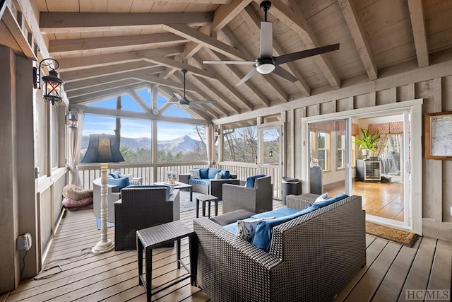 sunroom with ceiling fan, a mountain view, lofted ceiling with beams, and wood ceiling