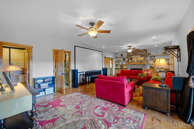 living room featuring light hardwood / wood-style flooring, ceiling fan, and a fireplace