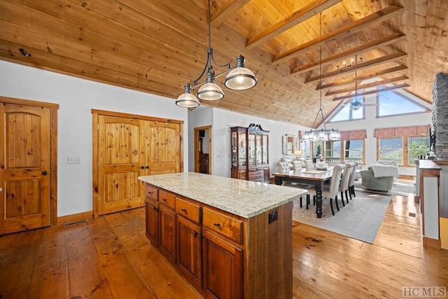 kitchen featuring light stone counters, light wood-type flooring, a kitchen island, decorative light fixtures, and wood ceiling