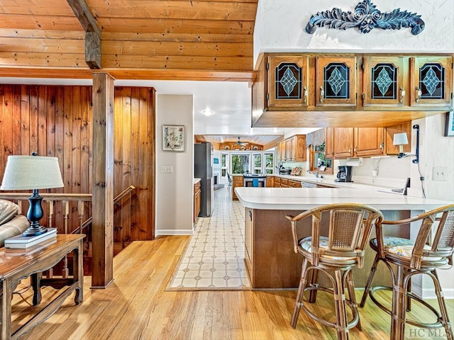 kitchen featuring a breakfast bar area, stainless steel refrigerator, light hardwood / wood-style floors, wooden ceiling, and kitchen peninsula