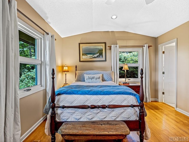 bedroom with hardwood / wood-style flooring, vaulted ceiling, a textured ceiling, and ceiling fan