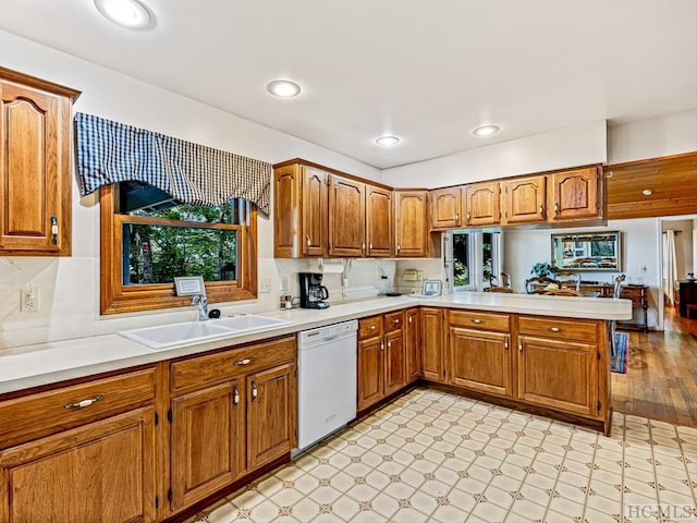 kitchen featuring white dishwasher, kitchen peninsula, sink, and a wealth of natural light