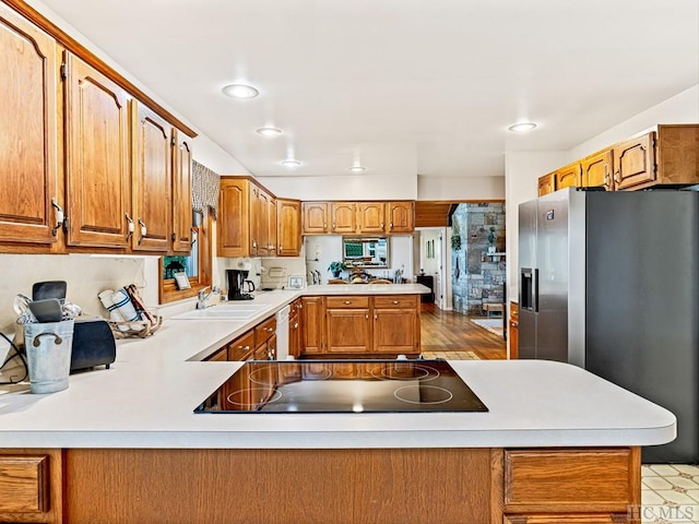 kitchen with kitchen peninsula, dishwasher, sink, black electric stovetop, and stainless steel fridge with ice dispenser