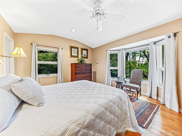 bedroom featuring multiple windows, light hardwood / wood-style flooring, lofted ceiling, and ceiling fan