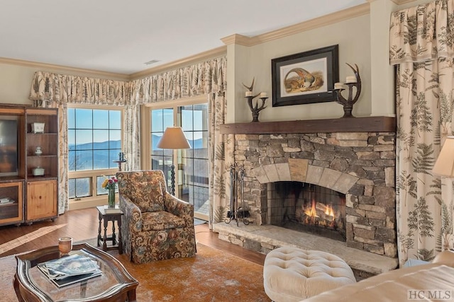 living room with a stone fireplace, wood-type flooring, and ornamental molding