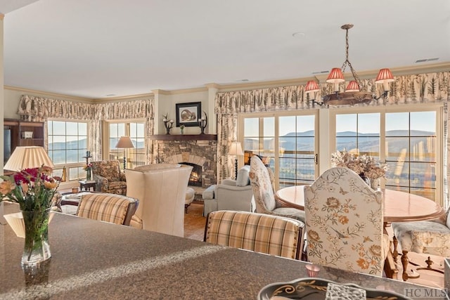 dining room featuring ornamental molding, a stone fireplace, and a mountain view