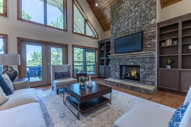 living room with a stone fireplace, wood ceiling, wood-type flooring, high vaulted ceiling, and built in features