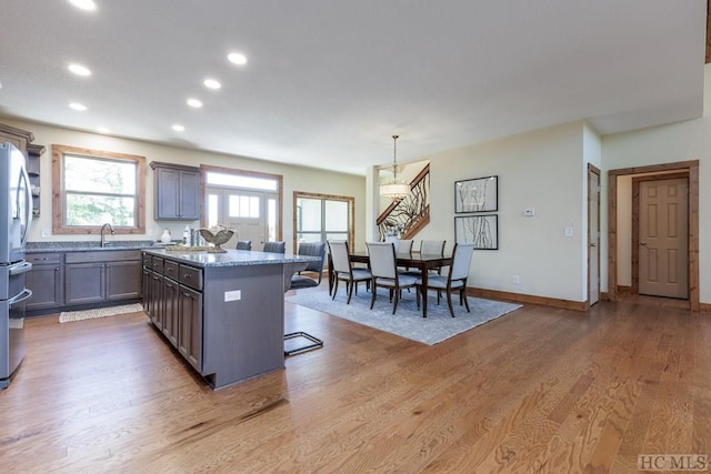 kitchen with hardwood / wood-style floors, decorative light fixtures, a kitchen bar, a center island, and light stone counters