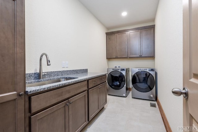 clothes washing area featuring light tile patterned flooring, cabinets, sink, and washer and dryer