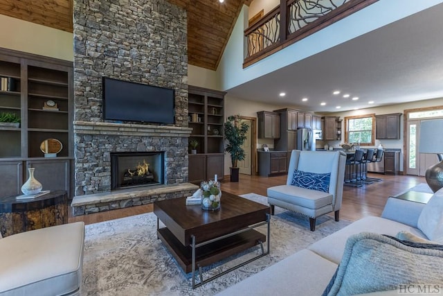 living room with a fireplace, high vaulted ceiling, light hardwood / wood-style flooring, and wooden ceiling