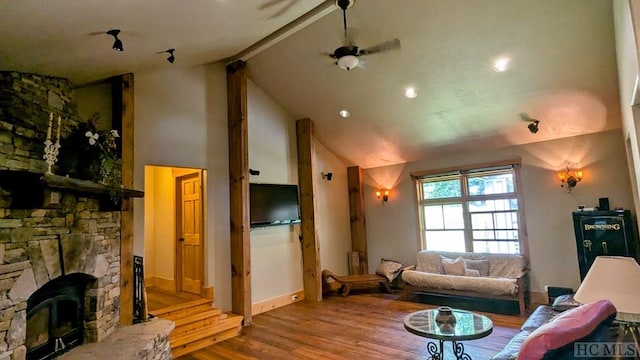 living room featuring hardwood / wood-style flooring, a stone fireplace, and high vaulted ceiling