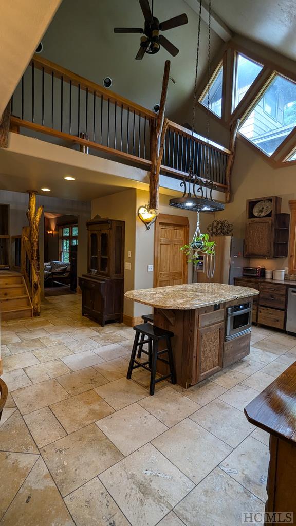 kitchen with ceiling fan, a center island, high vaulted ceiling, and dishwasher