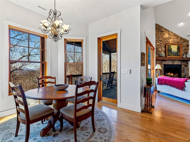 130 Cross Vine Dr, Tuckasegee, NC 28783 - dining space with visible vents, vaulted ceiling, light wood-style floors, a fireplace, and a notable chandelier