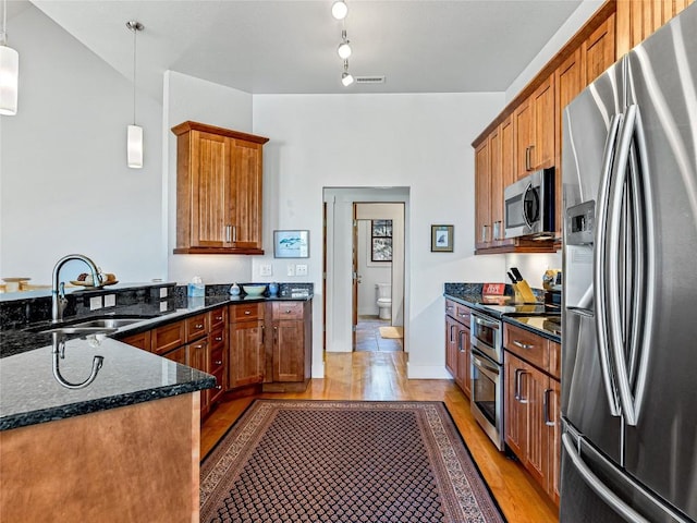 130 Cross Vine Dr, Tuckasegee, NC 28783 - kitchen featuring a sink, appliances with stainless steel finishes, brown cabinetry, dark stone countertops, and pendant lighting