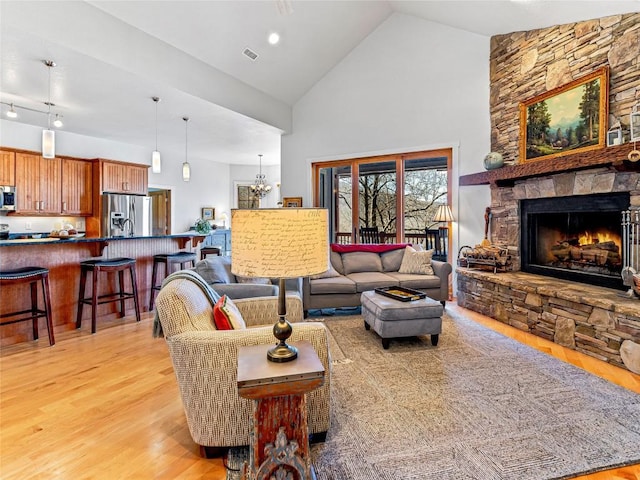 130 Cross Vine Dr, Tuckasegee, NC 28783 - living room featuring a chandelier, visible vents, a stone fireplace, high vaulted ceiling, and light wood-type flooring
