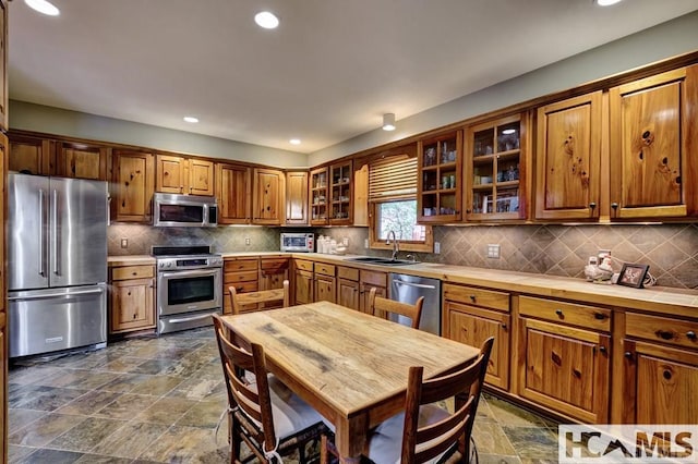 129 Cedar Creek Rd, Glenville, NC 28736 - kitchen featuring appliances with stainless steel finishes, brown cabinets, backsplash, glass insert cabinets, and recessed lighting