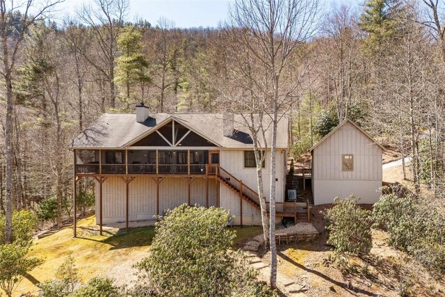 1034 E Rochester Dr, Cashiers, NC 28717 - rear view of property with stairway, a wooded view, a chimney, a wooden deck, and a sunroom