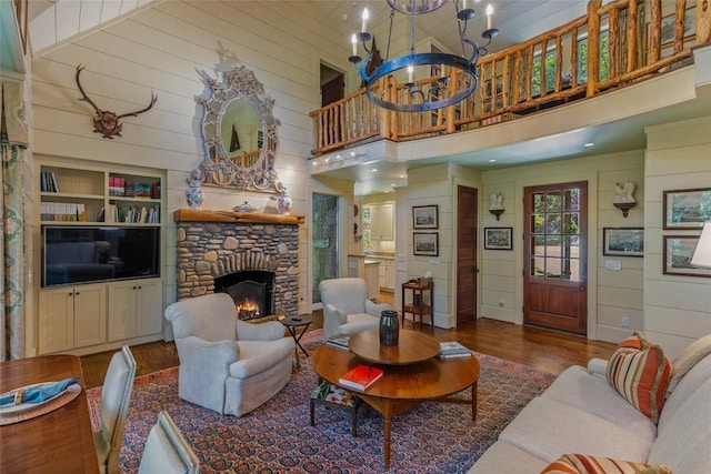131 Big Creek Ln, Highlands, NC 28741 - living area featuring wood finished floors, a stone fireplace, a towering ceiling, a chandelier, and wooden walls