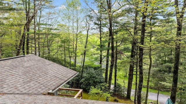 exterior space with roof with shingles and a forest view