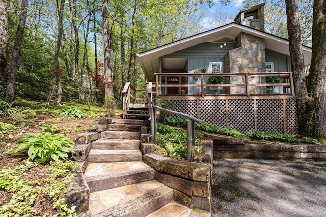 view of front of property featuring a wooden deck, stairway, board and batten siding, and stone siding