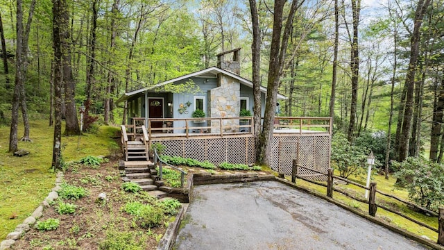 view of outdoor structure featuring stairway, a view of trees, and asphalt driveway