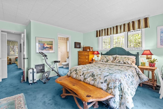 bedroom with carpet floors, multiple windows, and ensuite bath