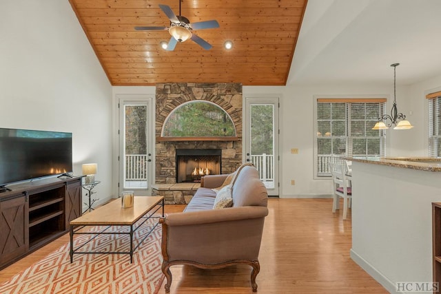 living room featuring a fireplace, wood ceiling, light hardwood / wood-style flooring, and ceiling fan with notable chandelier