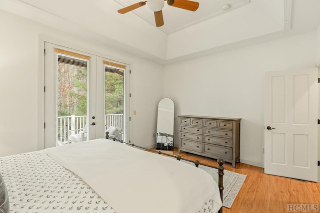 bedroom featuring access to exterior, a tray ceiling, light hardwood / wood-style flooring, and ceiling fan