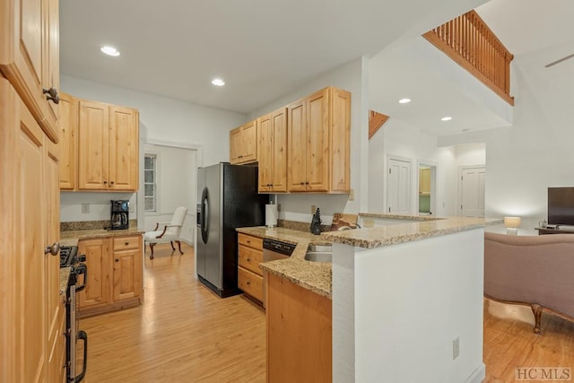 kitchen featuring light hardwood / wood-style flooring, appliances with stainless steel finishes, light stone counters, kitchen peninsula, and light brown cabinets