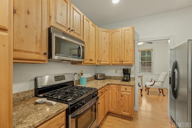 kitchen with light stone counters, light brown cabinetry, light hardwood / wood-style flooring, and stainless steel appliances