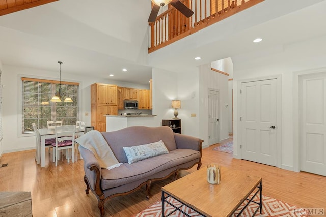 living room featuring high vaulted ceiling, a chandelier, and light wood-type flooring