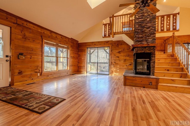 unfurnished living room featuring wood-type flooring, a fireplace, ceiling fan, and wood walls