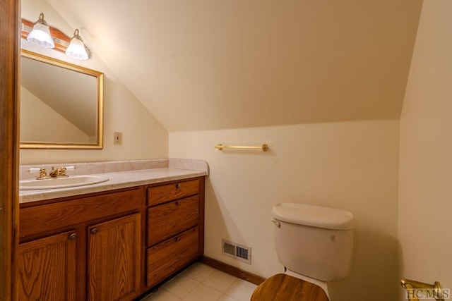 bathroom with lofted ceiling, vanity, tile patterned floors, and toilet