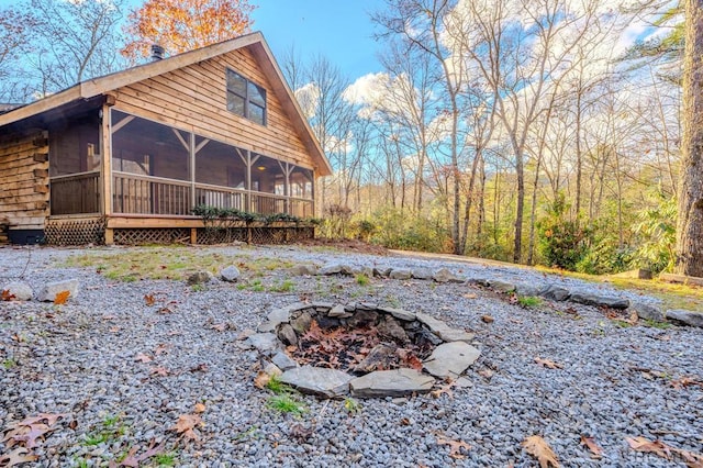 rear view of property with a fire pit and a sunroom