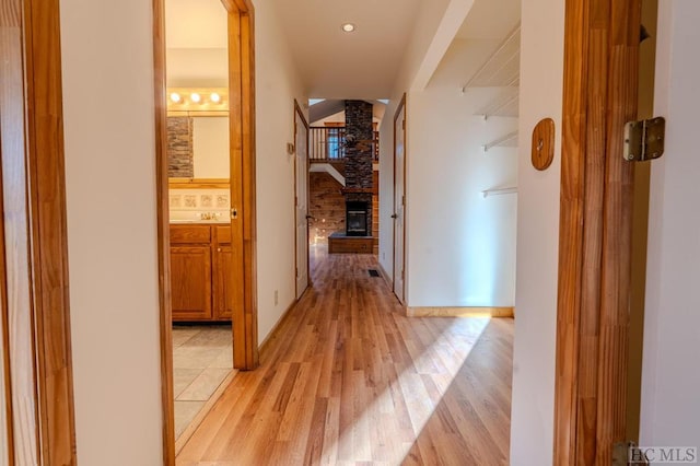 hallway with decorative columns, sink, and light hardwood / wood-style flooring