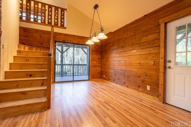 interior space with hardwood / wood-style flooring, vaulted ceiling, and wooden walls