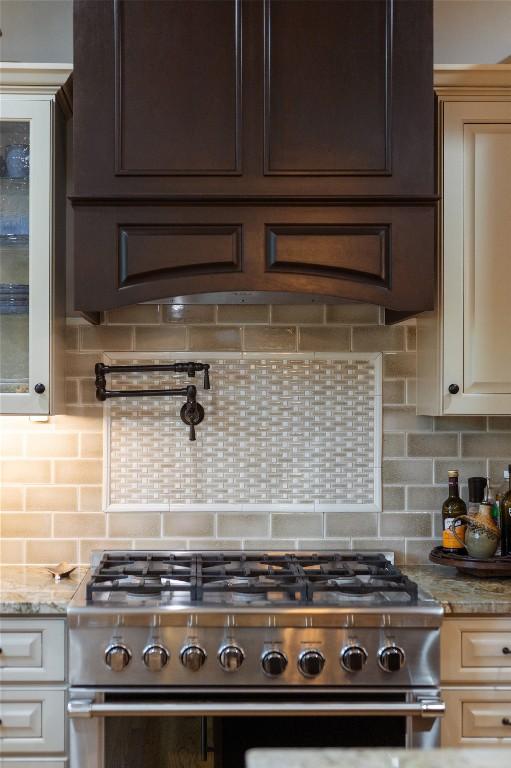 614 Fairway Dr, Lake Toxaway, NC 28747 - kitchen with high end stainless steel range oven, dark brown cabinetry, decorative backsplash, and light stone counters