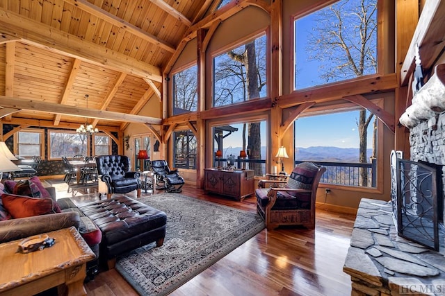 living room with a stone fireplace, high vaulted ceiling, a mountain view, wooden ceiling, and an inviting chandelier