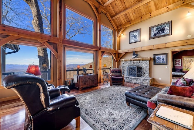 living room with hardwood / wood-style flooring, wood ceiling, a stone fireplace, and high vaulted ceiling